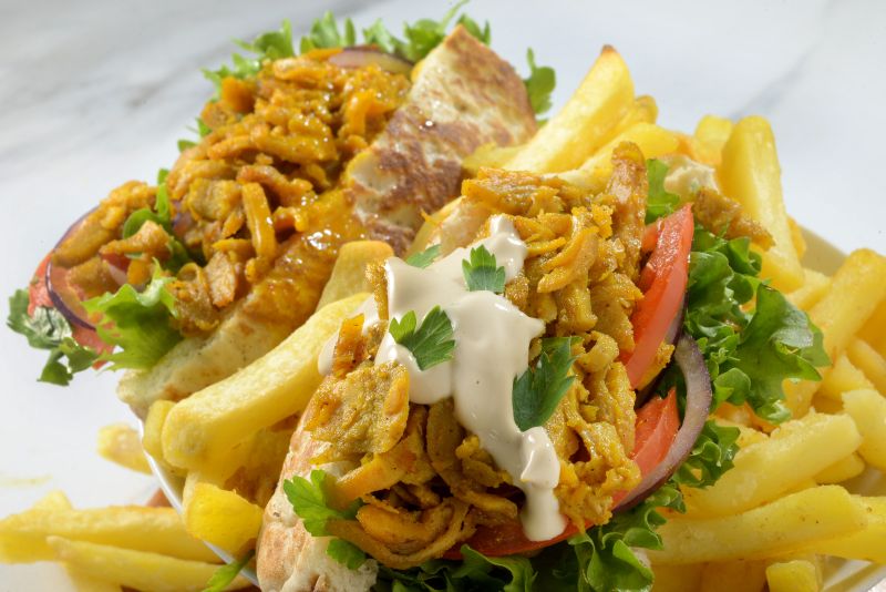 Shawarma-seasoned plant-based protein in a pita with fries, tahini and fresh salad