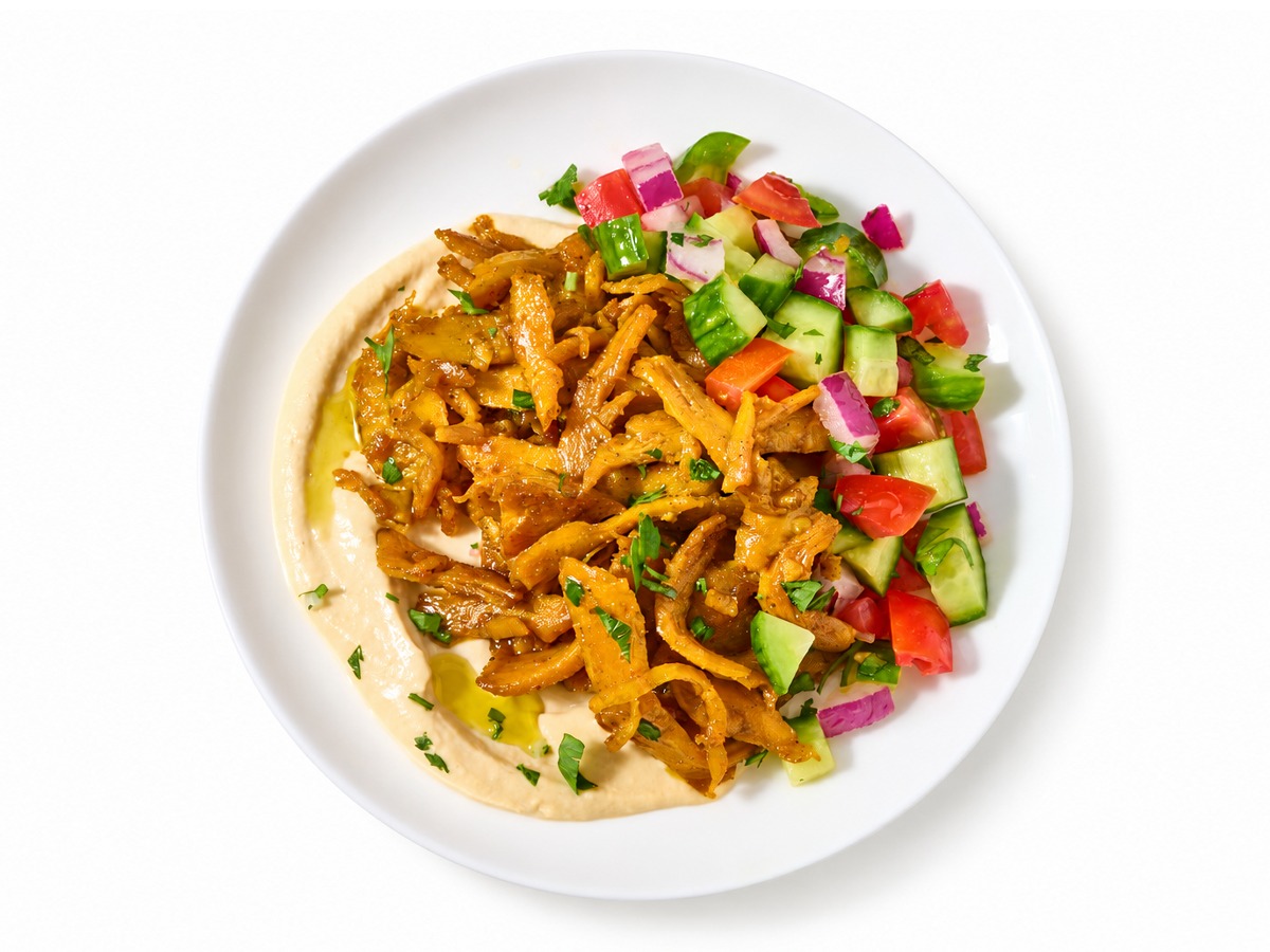 Shawarma-seasoned plant-based protein on hummus with Israeli salad