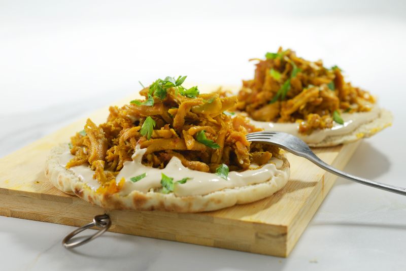 Shawarma-seasoned plant-based protein on pita with tahini and fresh herbs